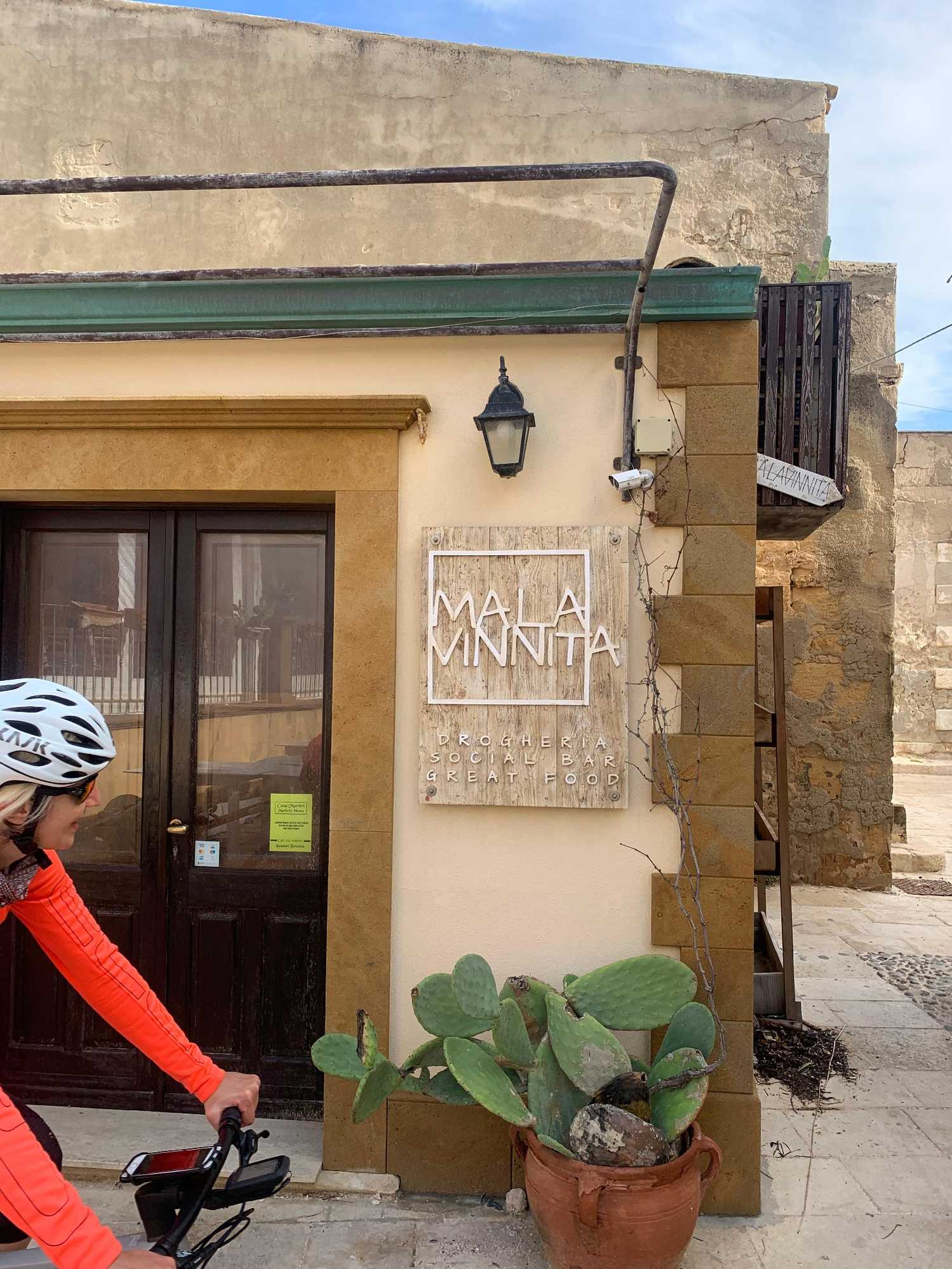 Sicily cycling tour woman biking past shop